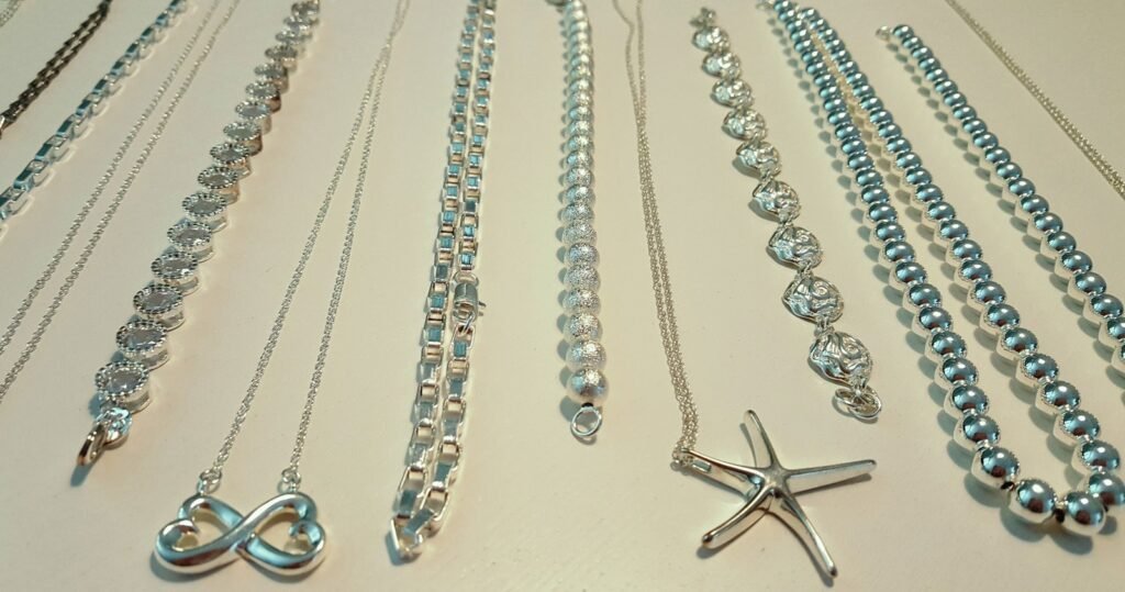 Colección de pulseras y collares de plata sobre fondo claro, con colgantes de infinito y estrella de mar