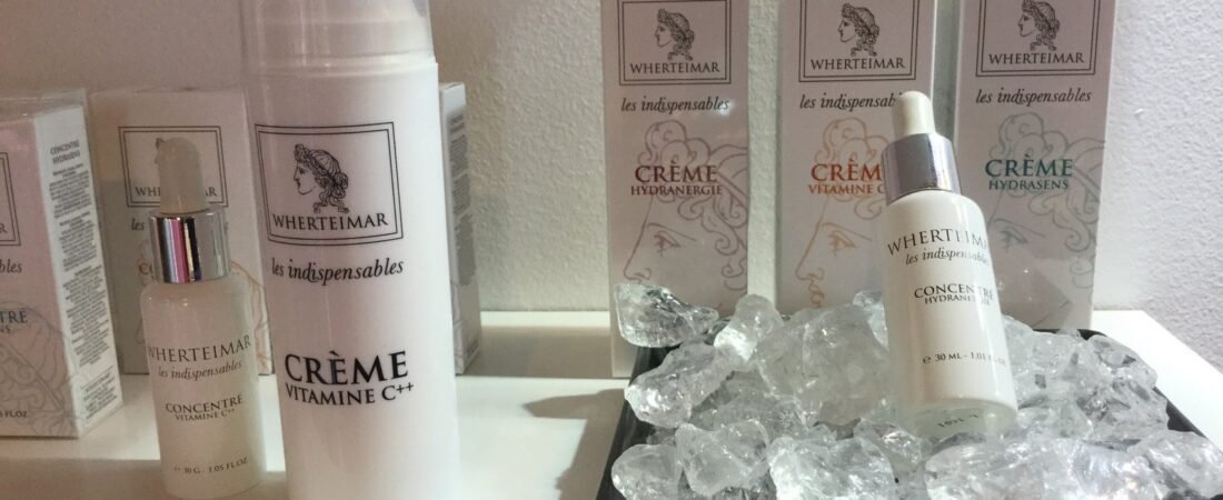 Crema de vitamina C y concentrados hidratantes de Wherteimar junto a una bandeja con cuarzos