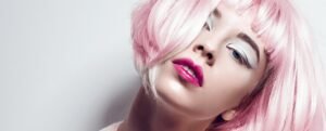 Modelo con peluca rosa pastel, sombra blanca y labios fucsia sobre fondo claro