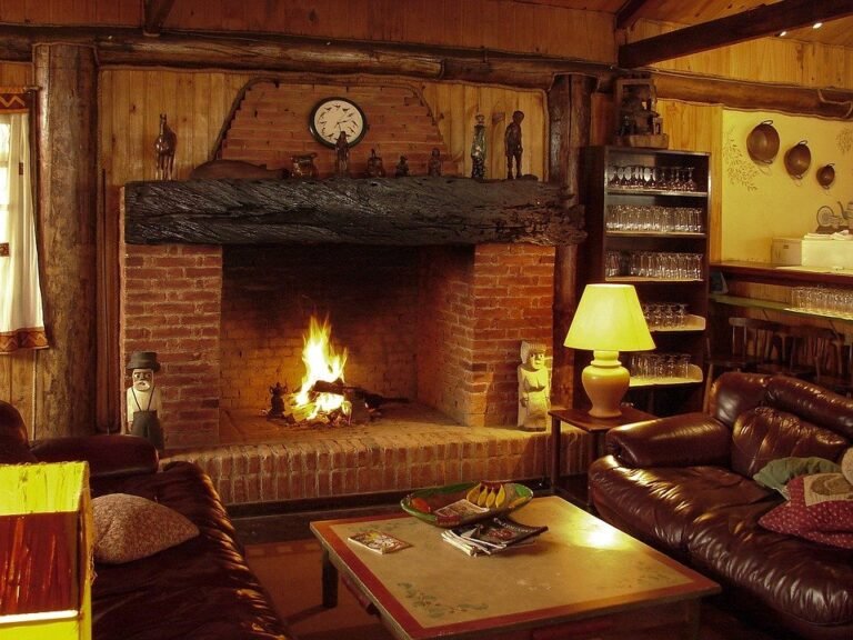 Salón rústico de madera con chimenea de ladrillo encendida, sofás de cuero y lámpara