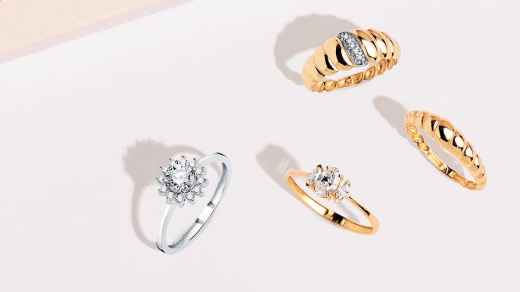 Cuatro anillos, tres dorados y uno plateado con circonitas, sobre fondo claro